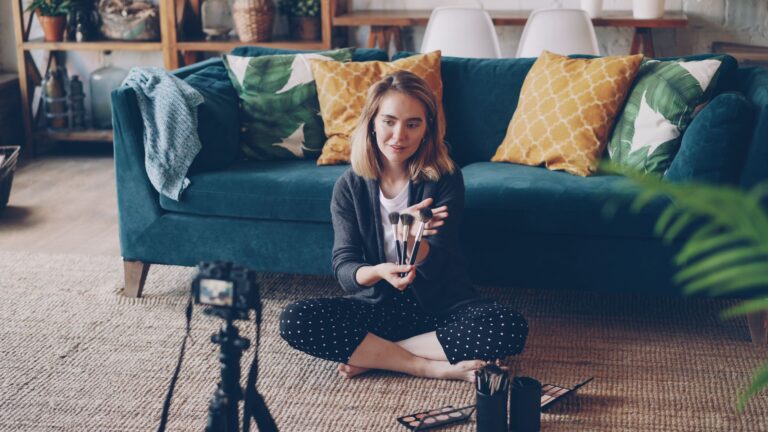 A woman filming a makeup tutorial in a cozy living room setting.